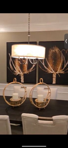 A chic dining room with elegant lighting, bold floral artwork, and decorative centerpieces on a dark table.