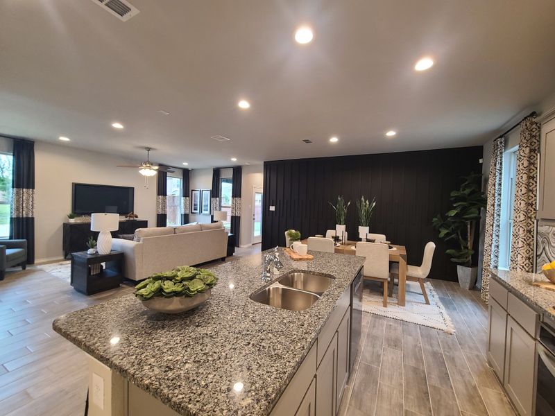 An open-concept living area with a granite island, cozy seating, and elegant dining space, enhanced by chic decor and warm lighting.