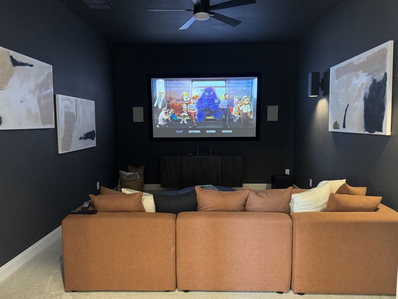 A cozy home theater with plush seating, dark walls, and a large screen for movie nights.