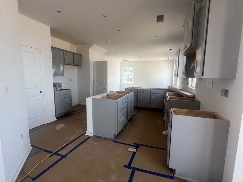A sleek kitchen under construction featuring gray cabinetry and white walls, offering a glimpse of modern design potential.