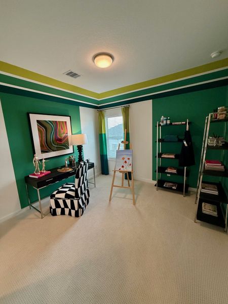 A vibrant room with bold green walls, modern art, a chic desk, and patterned chair, ideal for creative pursuits.