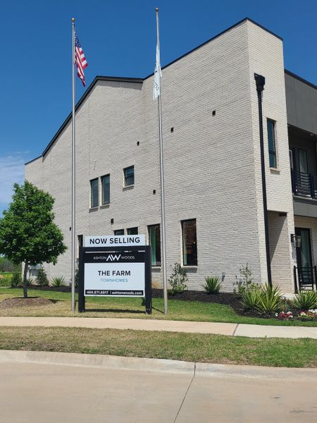 A modern white brick townhome with manicured landscaping in The Farm by Ashton Woods (Allen, TX).