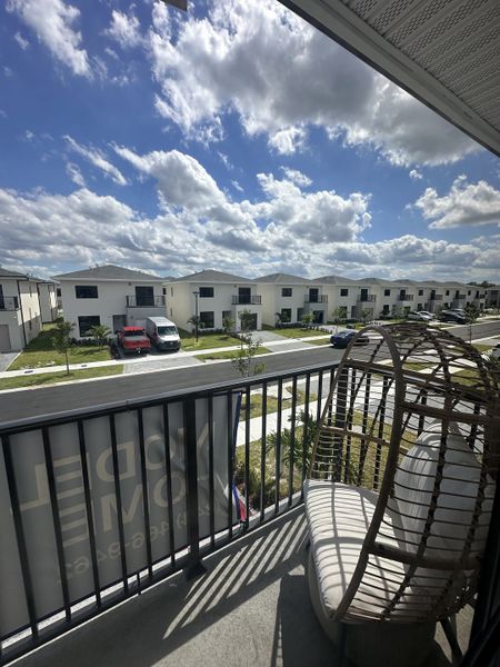 Modern white homes line a sunny street view in On Alba by Onx Homes, Florida City, FL, with a charming patio swing.