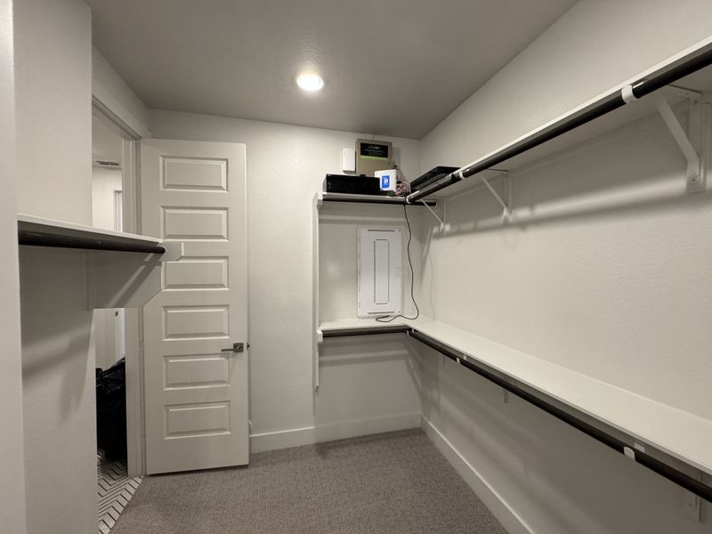 A spacious walk-in closet with built-in shelves and ample hanging space, featuring modern white walls and soft lighting. A spacious walk-in closet with built-in shelves and ample hanging space, featuring modern white walls and soft lighting.