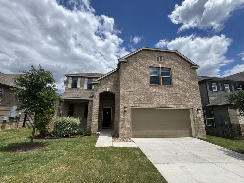 A beautiful brick home with a manicured lawn in McKinney Crossing by KB Home (Austin, TX).