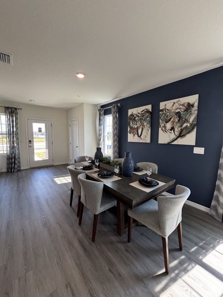 A sophisticated dining area with a bold navy feature wall, elegant decor, and modern seating in Avian Pointe Townhomes by D.R. Horton (Apopka, FL).