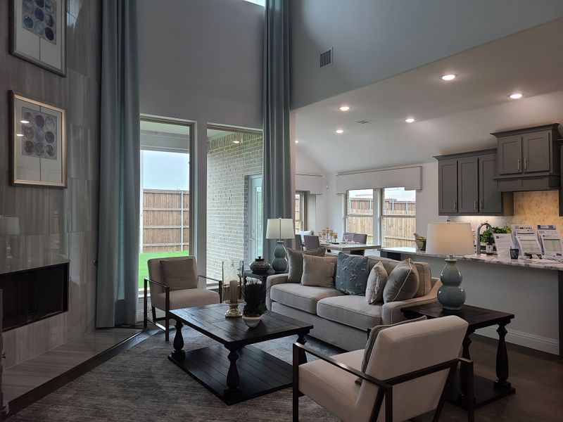 A modern living room with high ceilings, neutral tones, and elegant furnishings leading to a stylish kitchen.