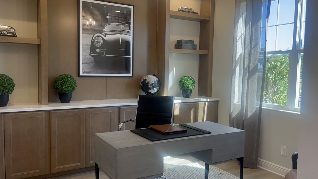 A modern office with a sleek desk, leather chair, decorative plants, and car-themed artwork. A modern office with a sleek desk, leather chair, decorative plants, and car-themed artwork.