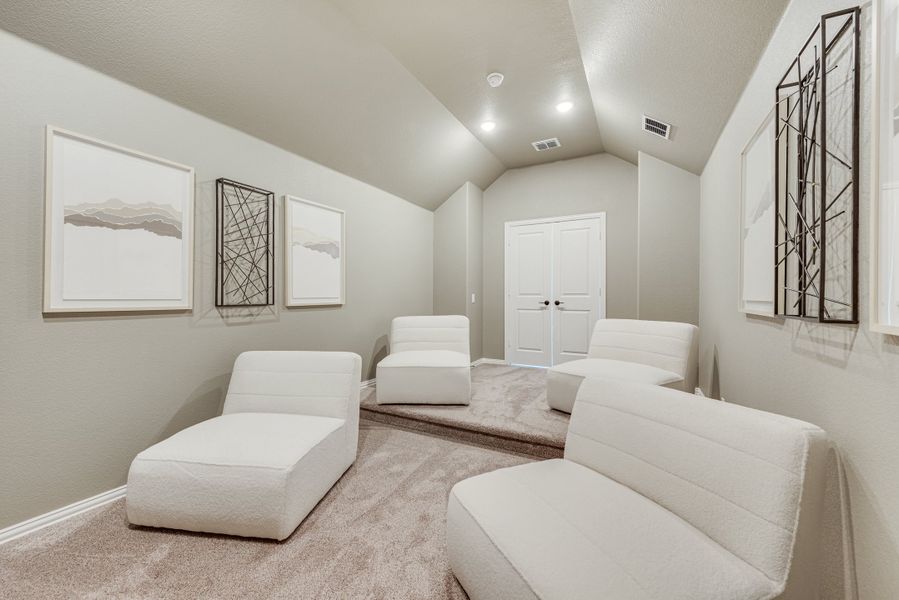 Media room with vaulted ceiling, white lounge chairs, and carpet flooring Media room with vaulted ceiling, white lounge chairs, and carpet flooring