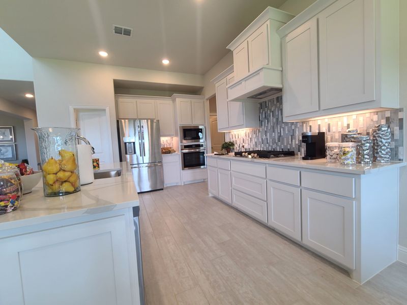 A modern kitchen with sleek white cabinets, stainless steel appliances, and a stylish tile backsplash.
