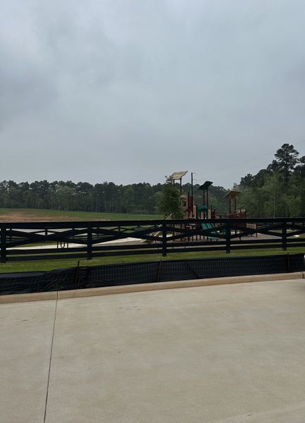 A scenic playground view surrounded by lush greenery in Sagecrest Preserve by KB Home (Conroe, TX).