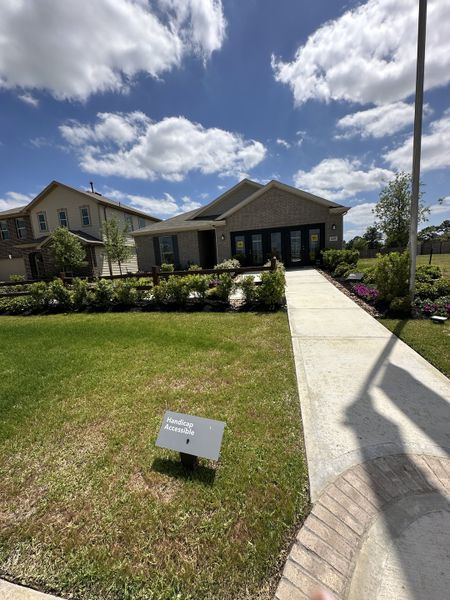 A charming brick home with lush landscaping and accessible walkway in Oakwood Trails by KB Home (Tomball, TX).