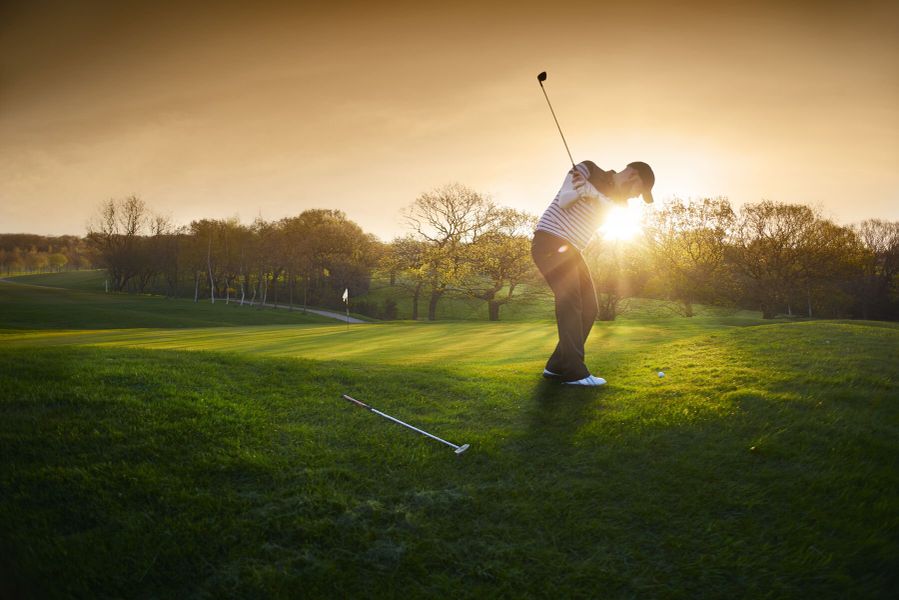 Man playing golf at sunset