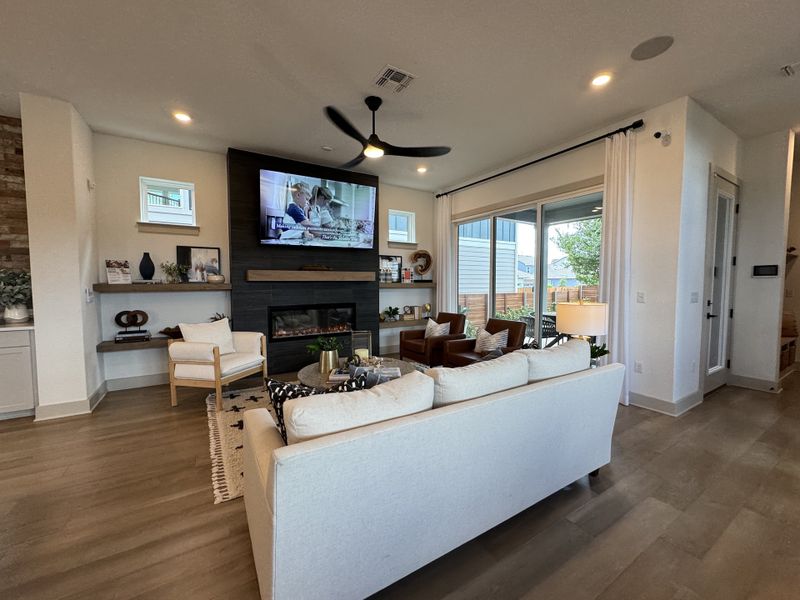 A modern living room with a cozy fireplace, sleek furnishings, and large windows opening to a patio view.