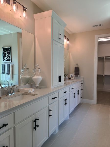 A modern bathroom with dual sinks, sleek white cabinetry, elegant lighting, and a spacious walk-in closet. A modern bathroom with dual sinks, sleek white cabinetry, elegant lighting, and a spacious walk-in closet.