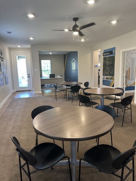 A modern meeting room with round tables, black chairs, and soft lighting creates a welcoming space.