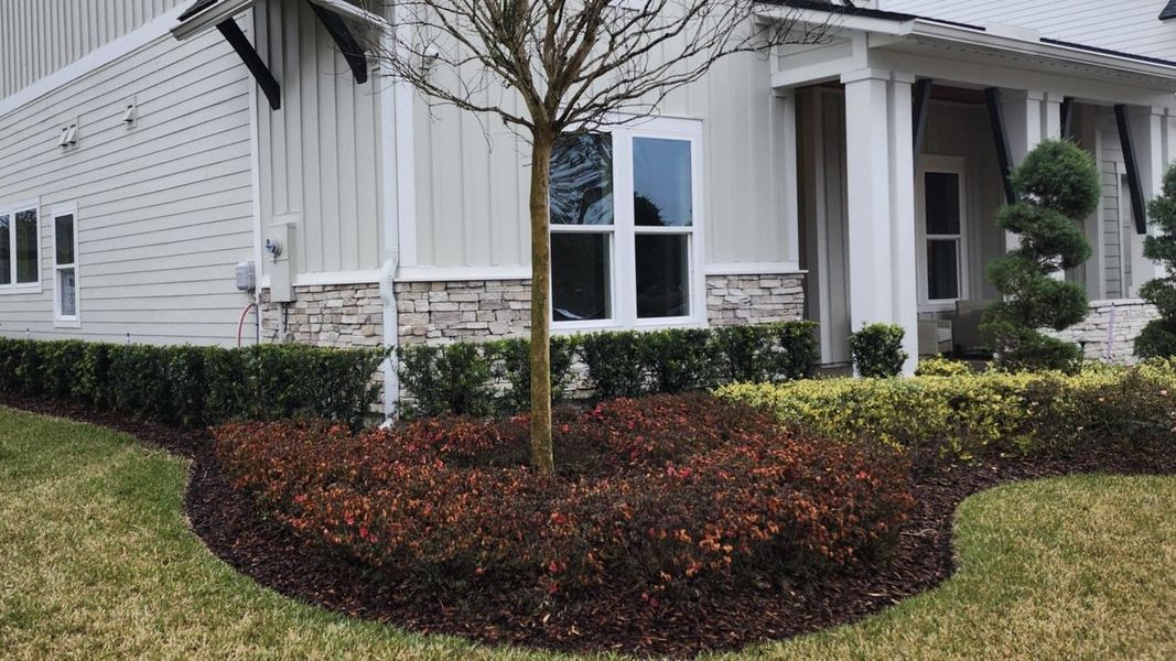 A beautiful home with stone accents and lush landscaping in SilverLeaf: Silver Falls Townhomes at Silverleaf by Lennar (St. Augustine, FL).