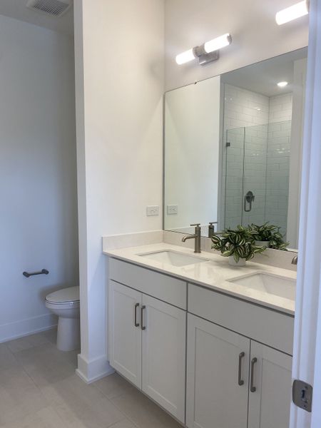 Elegant bathroom with dual sinks, modern fixtures, large mirror, and a stylish shower. Elegant bathroom with dual sinks, modern fixtures, large mirror, and a stylish shower.