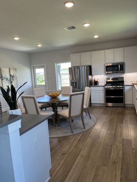 A modern kitchen with sleek stainless steel appliances, cozy dining area, and wood flooring.