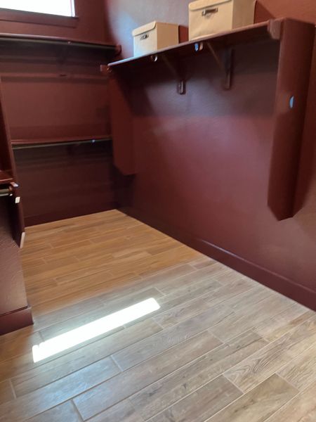 A spacious closet with rich brown walls, wooden flooring, and ample shelving for storage.