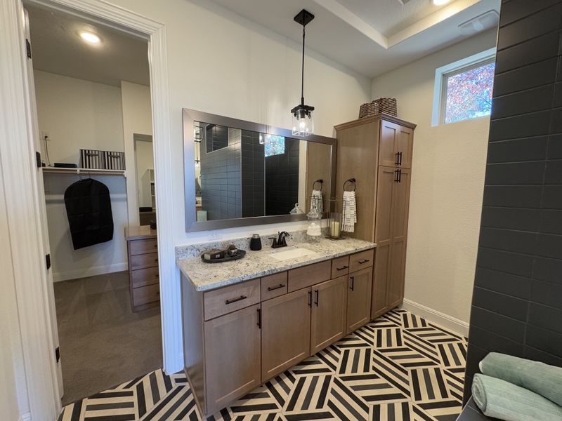A modern bathroom features geometric tile flooring, a granite countertop, and natural wood cabinetry with sleek accents. A modern bathroom features geometric tile flooring, a granite countertop, and natural wood cabinetry with sleek accents.