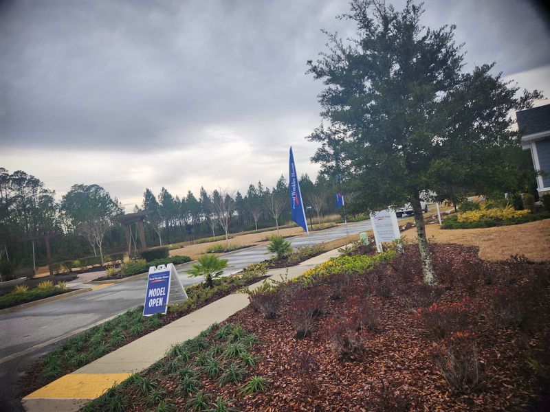 Inviting landscape with lush greenery and a "Model Open" sign in Tributary 70' by David Weekley Homes, Yulee, FL.