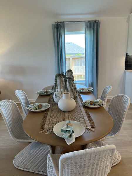 Elegant dining room with a wooden table, woven chairs, and soft blue accents. Elegant dining room with a wooden table, woven chairs, and soft blue accents.