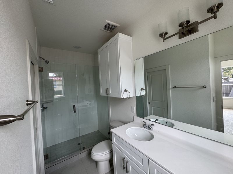 A sleek bathroom with a glass-enclosed shower, modern fixtures, and ample vanity space.