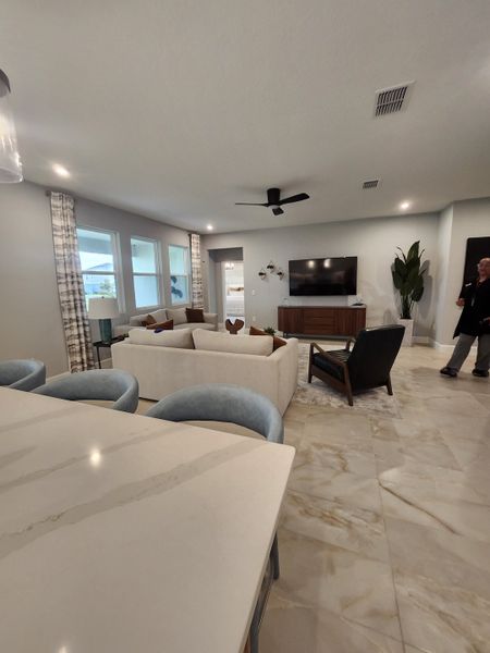 A spacious living room with a sleek TV unit, plush seating, and elegant marble floors.