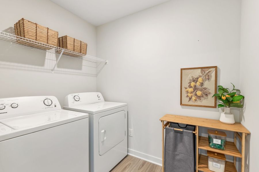 A white room with a table and a white wall with a basket and a plant on it.