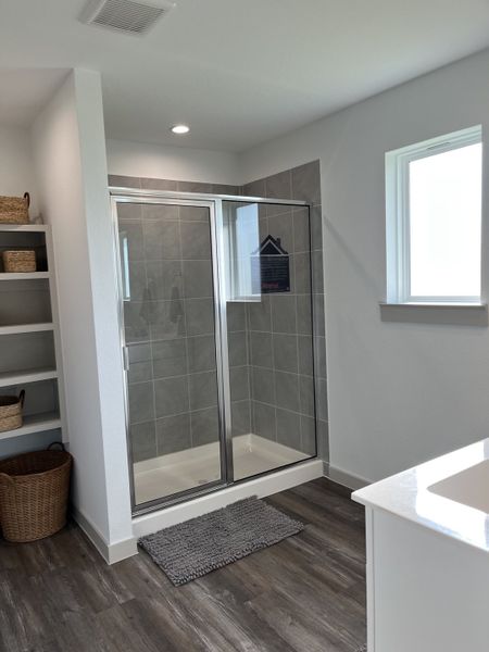 A modern bathroom with a sleek glass shower, gray tiles, and wood flooring creating a stylish and functional space.
