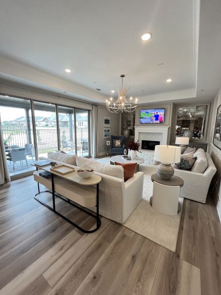 A spacious living room with elegant chandelier, cozy seating, and large windows offering plenty of natural light. A spacious living room with elegant chandelier, cozy seating, and large windows offering plenty of natural light.