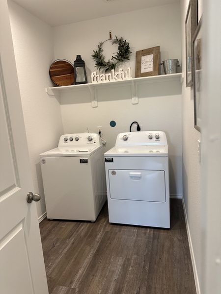 A cozy laundry room featuring a washer and dryer, wood flooring, and decorative shelving for a stylish touch.