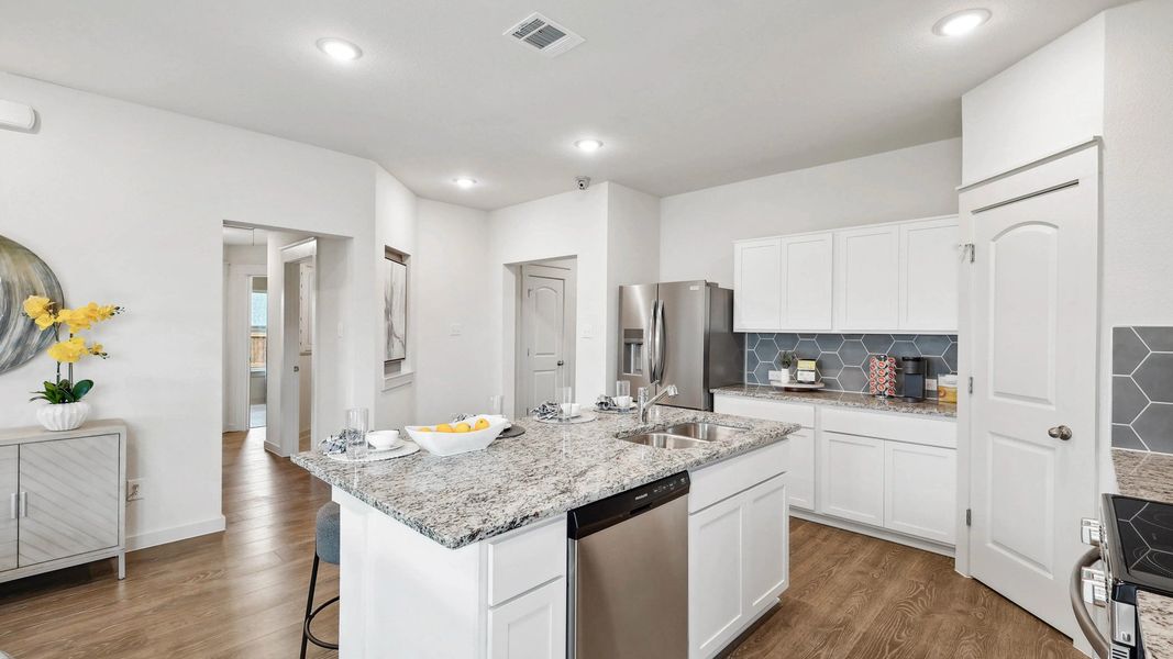 Experience luxury with granite countertops and hexagonal tile backsplash in Still Water Lake Estates' stylish kitchen.