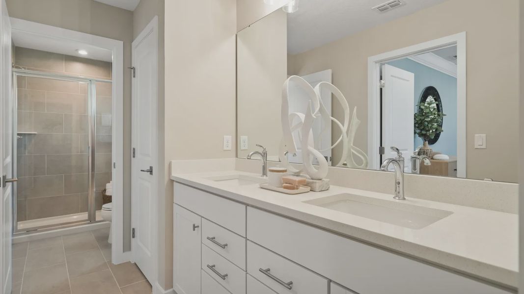 The primary suite at Cyrene at Harmony by DRB Homes features a spacious bathroom with dual sinks The primary suite at Cyrene at Harmony by DRB Homes features a spacious bathroom with dual sinks