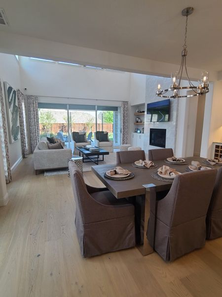 Elegant open-concept living and dining area with natural light, modern chandelier, and cozy seating.