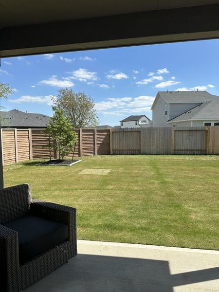 A tranquil backyard with lush grass, wooden fencing, and cozy dark wicker seating, perfect for relaxation and outdoor enjoyment. A tranquil backyard with lush grass, wooden fencing, and cozy dark wicker seating, perfect for relaxation and outdoor enjoyment.