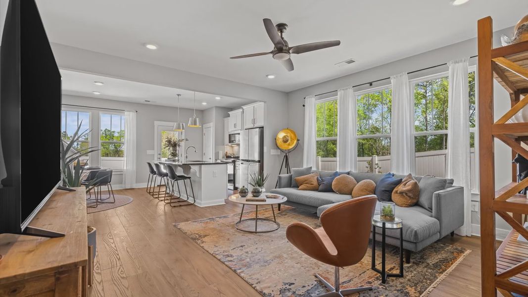 Colorfully decorated family room with elevated ceilings, hardwood flooring, and multiple large windows in two story townhome Colorfully decorated family room with elevated ceilings, hardwood flooring, and multiple large windows in two story townhome