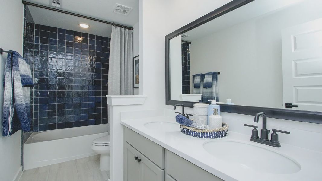 Exquisite bathroom featuring elegant navy tiles and dual sinks at Colony at Pinehurst.