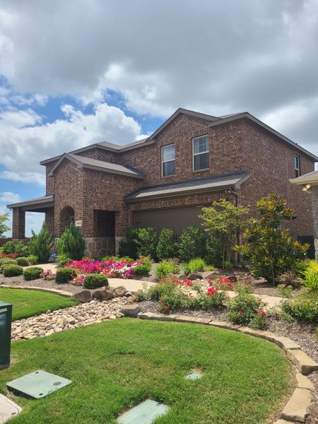 A charming brick home with vibrant landscaping in the Riverfield community by D.R. Horton (Josephine, TX).