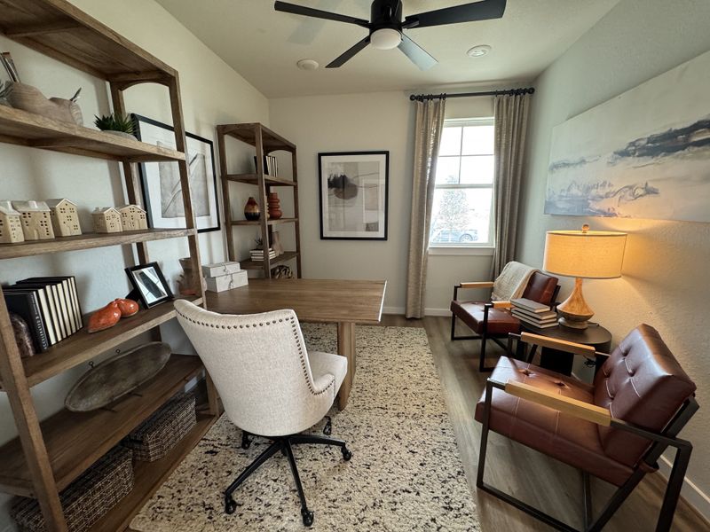 A cozy home office with wooden shelves, a large desk, modern art, and stylish seating. A cozy home office with wooden shelves, a large desk, modern art, and stylish seating.