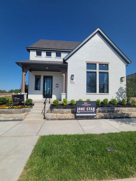 Charming white brick home with a gabled roof and manicured landscaping in Hillside Village 40s by HistoryMaker Homes (Celina, TX).