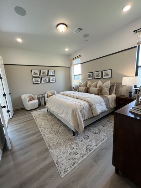 A cozy bedroom featuring elegant decor, a plush bed, soft lighting, and a stylish area rug on hardwood floors. A cozy bedroom featuring elegant decor, a plush bed, soft lighting, and a stylish area rug on hardwood floors.