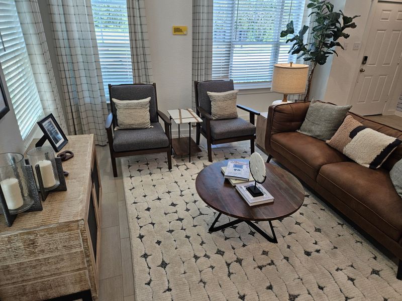 A cozy living room featuring a plush brown sofa, patterned rug, and elegant decor with ample natural light from large windows. A cozy living room featuring a plush brown sofa, patterned rug, and elegant decor with ample natural light from large windows.