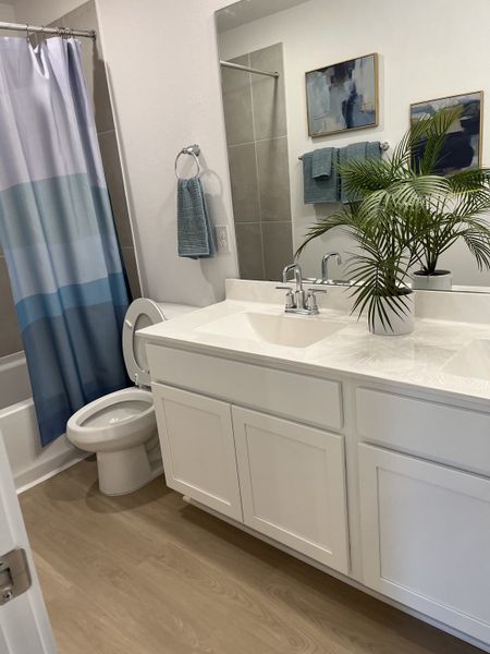 A modern bathroom with a sleek white vanity, wood flooring, and stylish blue accents. A modern bathroom with a sleek white vanity, wood flooring, and stylish blue accents.