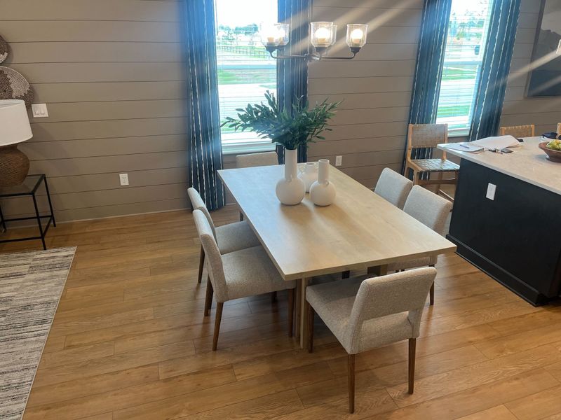 A modern dining area with a sleek wooden table, contemporary chairs, and elegant lighting. A modern dining area with a sleek wooden table, contemporary chairs, and elegant lighting.