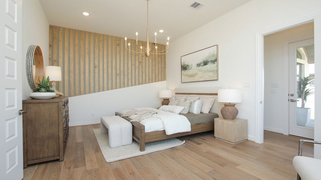 Luxury Sunterra bedroom boasts a tray ceiling, sophisticated accent wall, and plush bedding for a serene retreat.