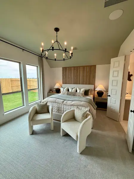 A cozy bedroom with a plush bed, soft carpet, modern chandelier, and elegant seating by the window for a relaxing ambiance. A cozy bedroom with a plush bed, soft carpet, modern chandelier, and elegant seating by the window for a relaxing ambiance.