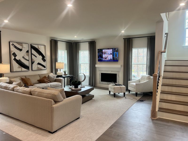 A cozy living room featuring a large sofa, abstract art, a modern fireplace, and stylish lighting.