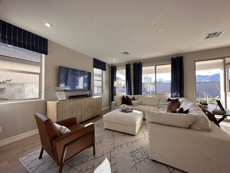 A bright living room featuring a large sectional, cozy armchair, and expansive windows, enhanced by modern decor.